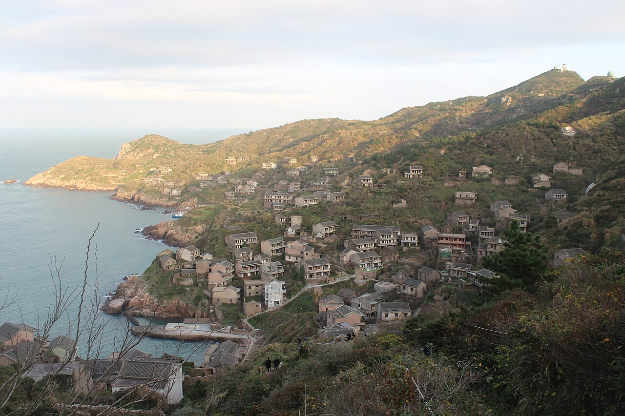 Abandoned stone houses on a hillside in Houtouwan covered almost entirely in green vines