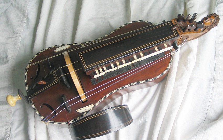 A hurdy-gurdy, a stringed instrument sounded by a crank-driven rosined wheel