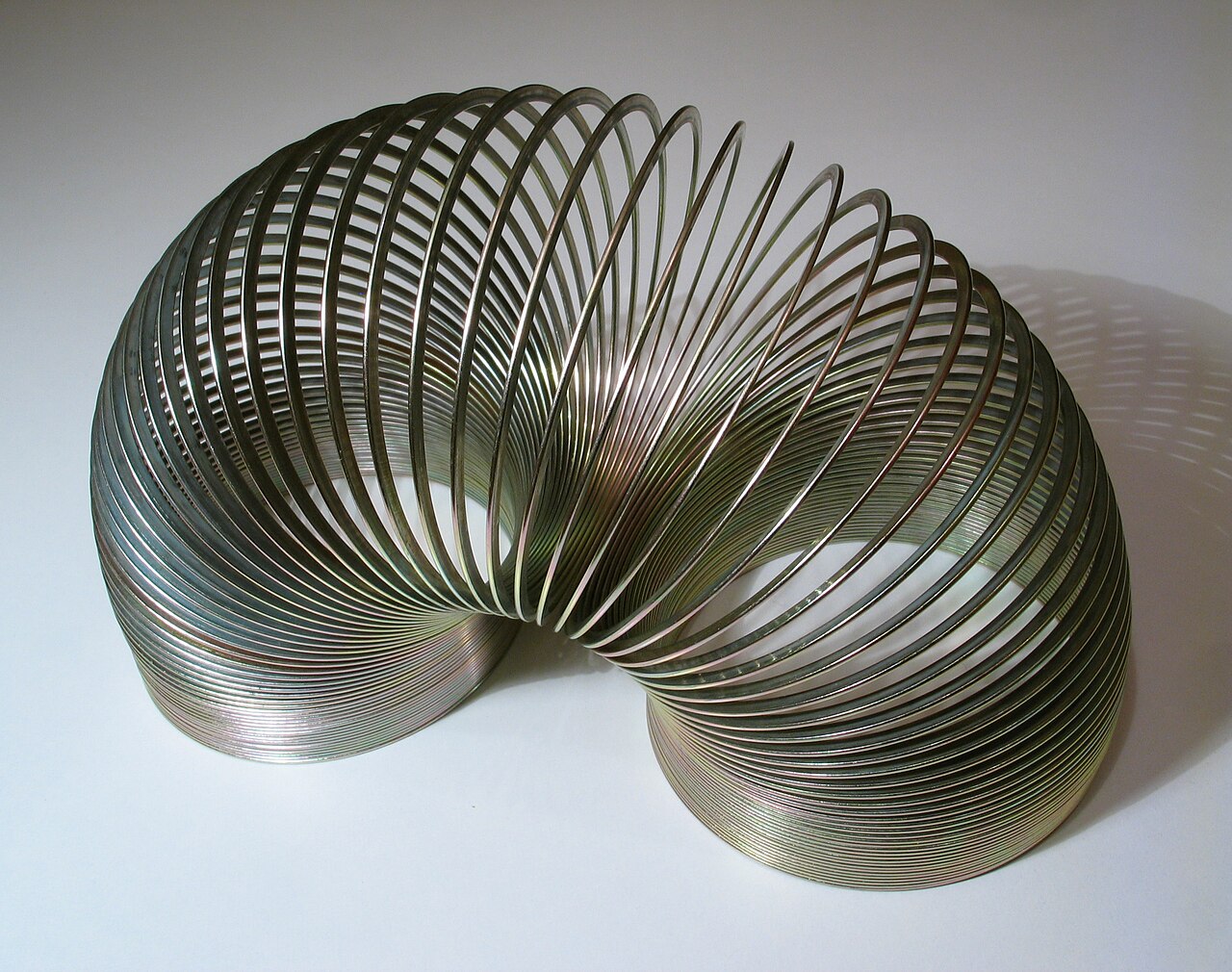 A classic metal Slinky toy, a coiled steel spring, resting on a surface