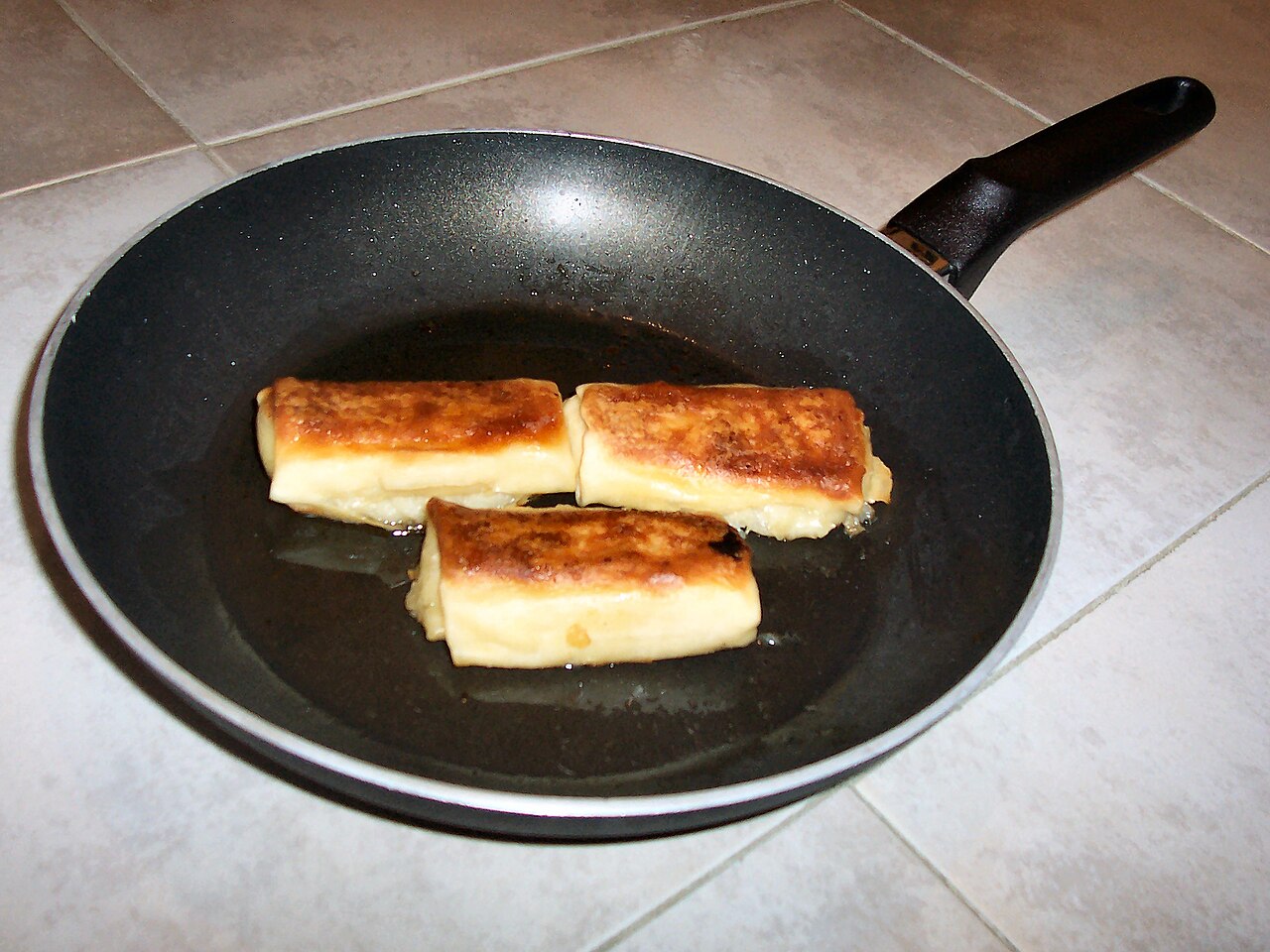 A frying pan with a dark non-stick coating on its cooking surface