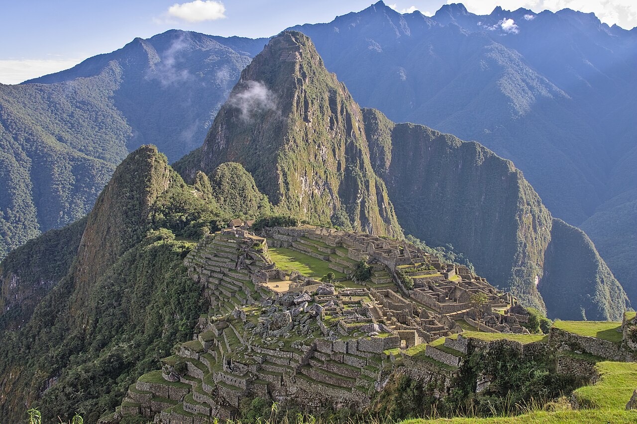 The Inca citadel of Machu Picchu with stone terraces on a ridge between green peaks
