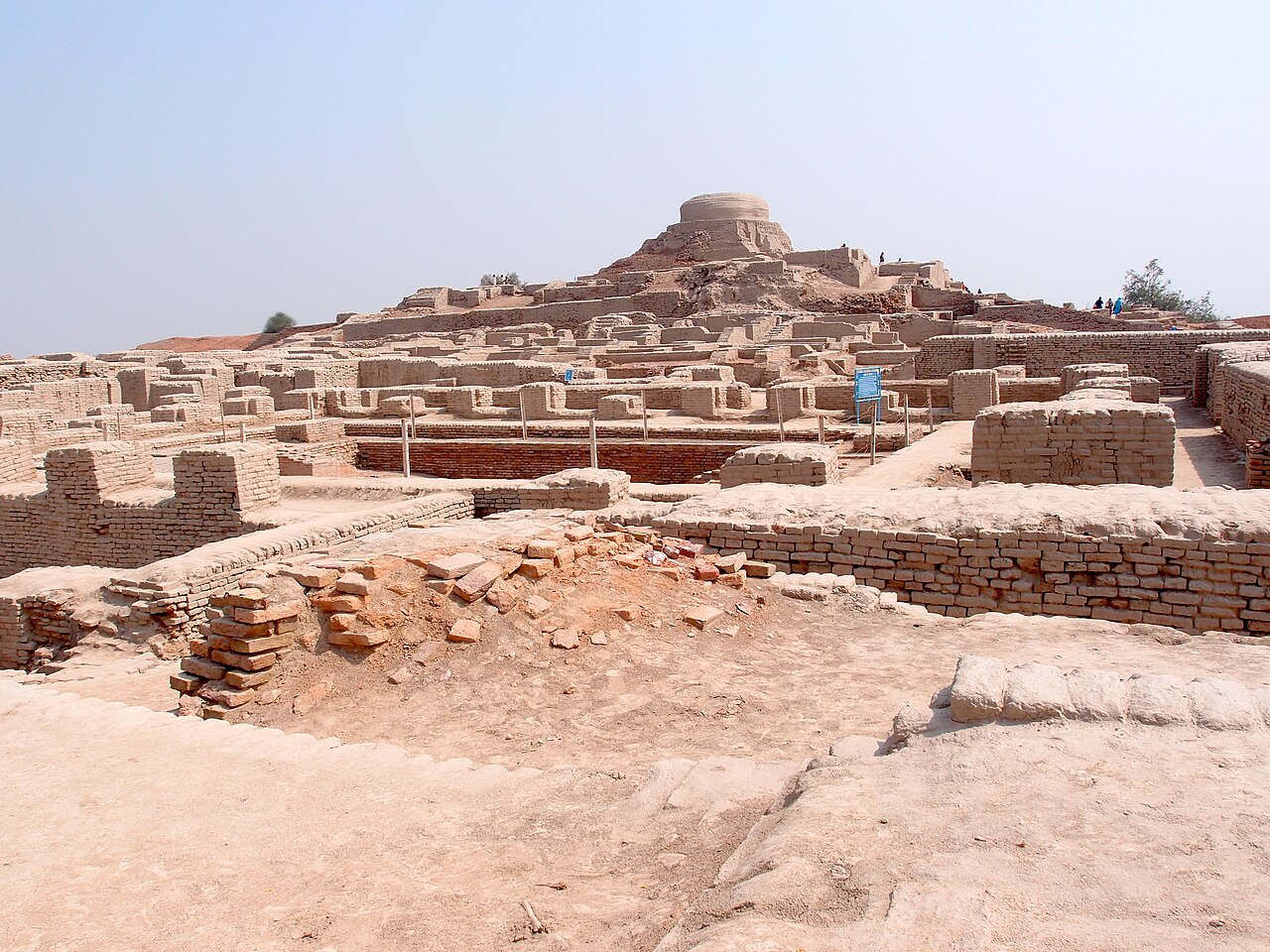 Excavated brick walls and streets of Mohenjo-daro beneath a later Buddhist stupa mound