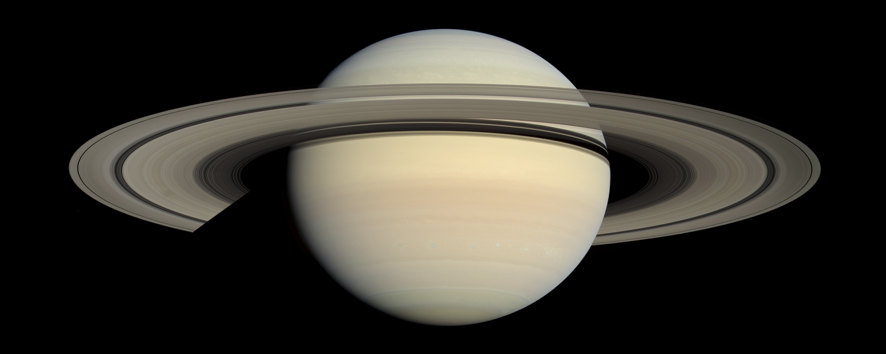The planet Saturn with its broad, pale golden ring system seen from space