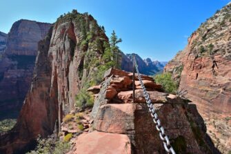 Hikers gripping chains along the narrow sandstone ridge of the Angels Landing trail in Zion National Park
