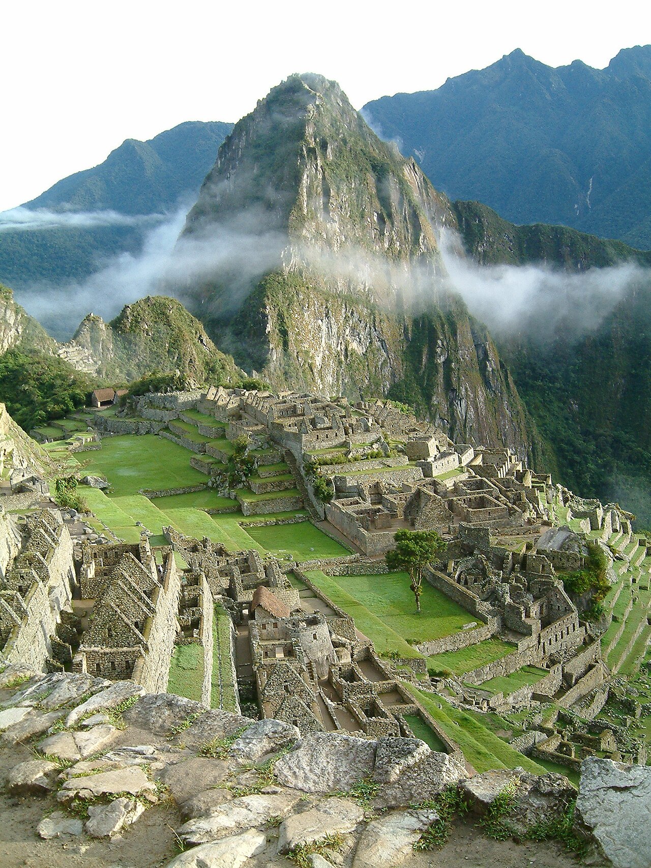 The steep green peak of Huayna Picchu towering over the ruins of Machu Picchu