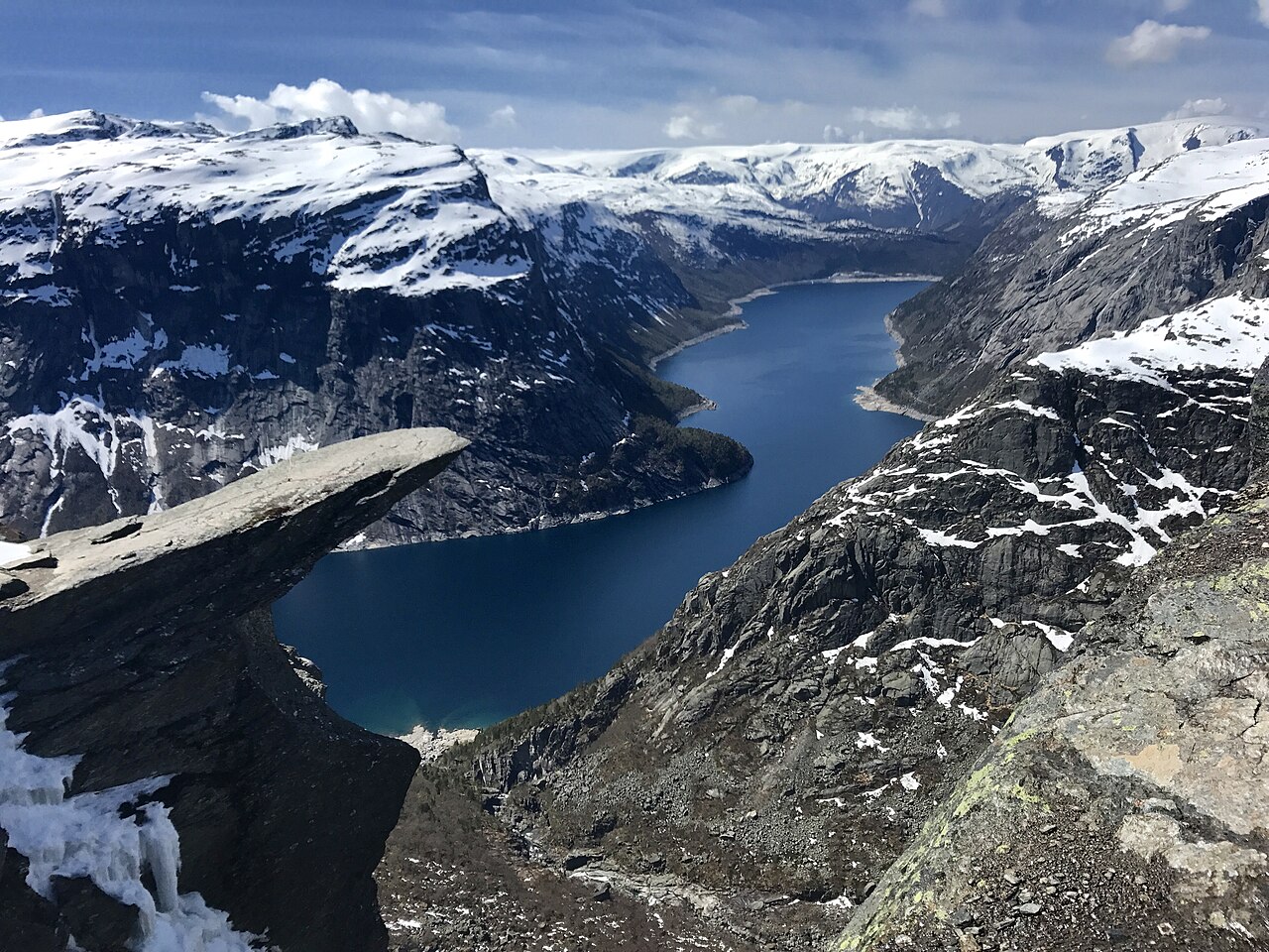 A flat rock ledge called Trolltunga projecting over a lake far below in Norway