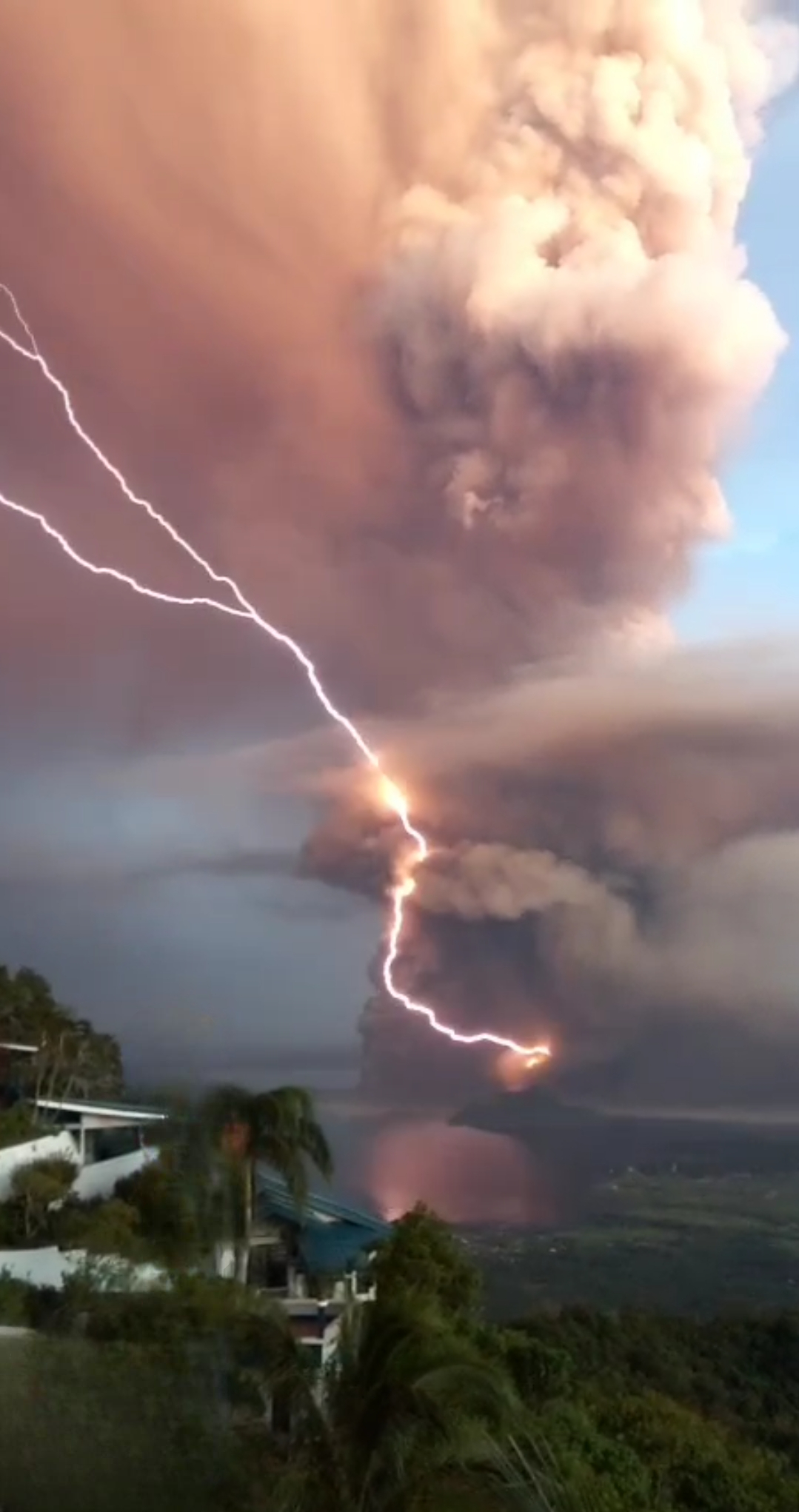 Bolts of lightning flashing inside a dark ash plume above an erupting volcano