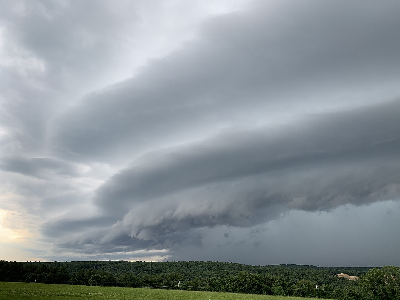 A long, horizontal tube-shaped roll cloud stretching low across the sky
