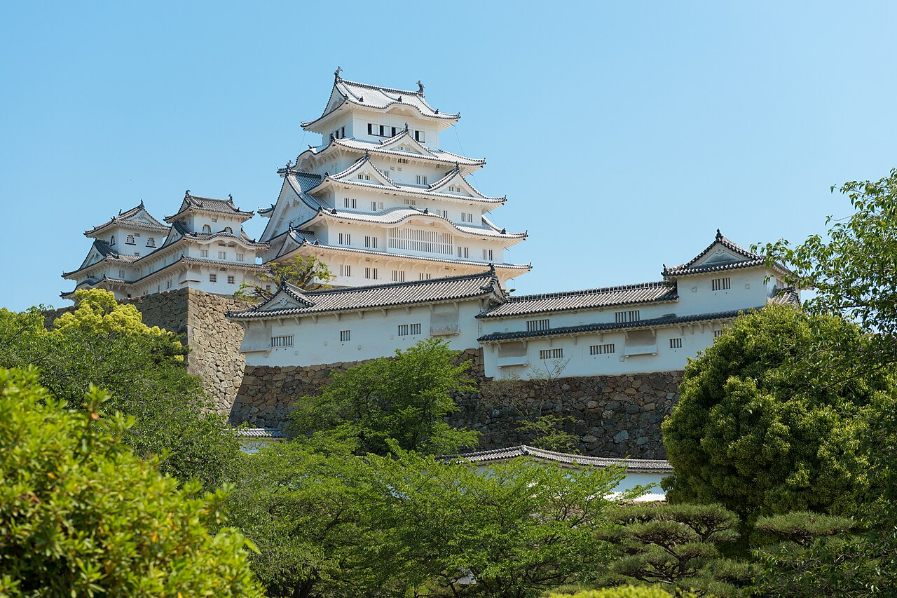 The white multi-tiered main keep of Himeji Castle rising above stone walls in Japan