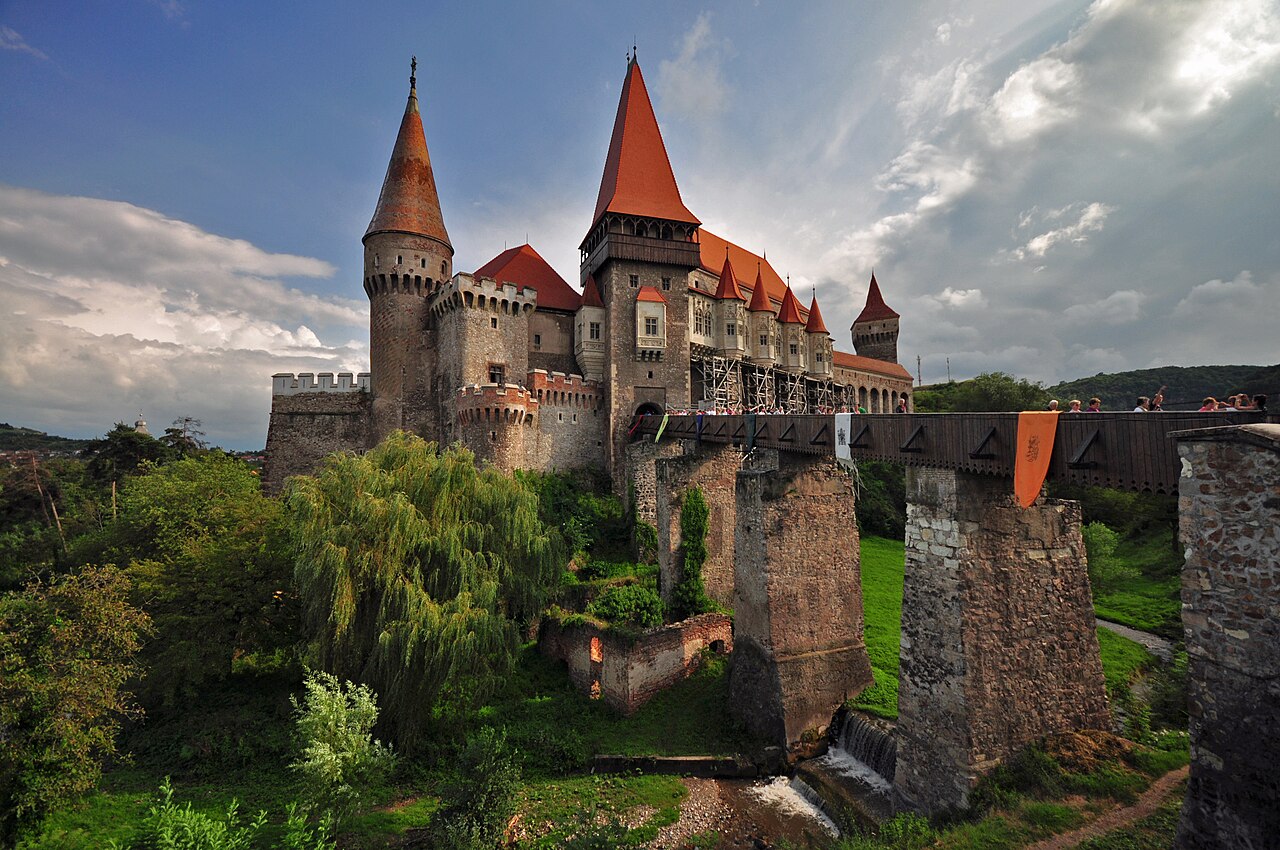Corvin Castle in Hunedoara, Romania, with Gothic towers and a long bridge on stone piers