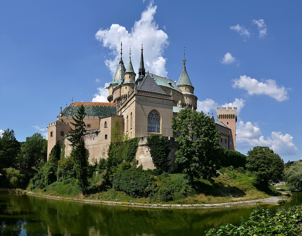 Bojnice Castle in Slovakia with pointed towers and steep roofs above trees