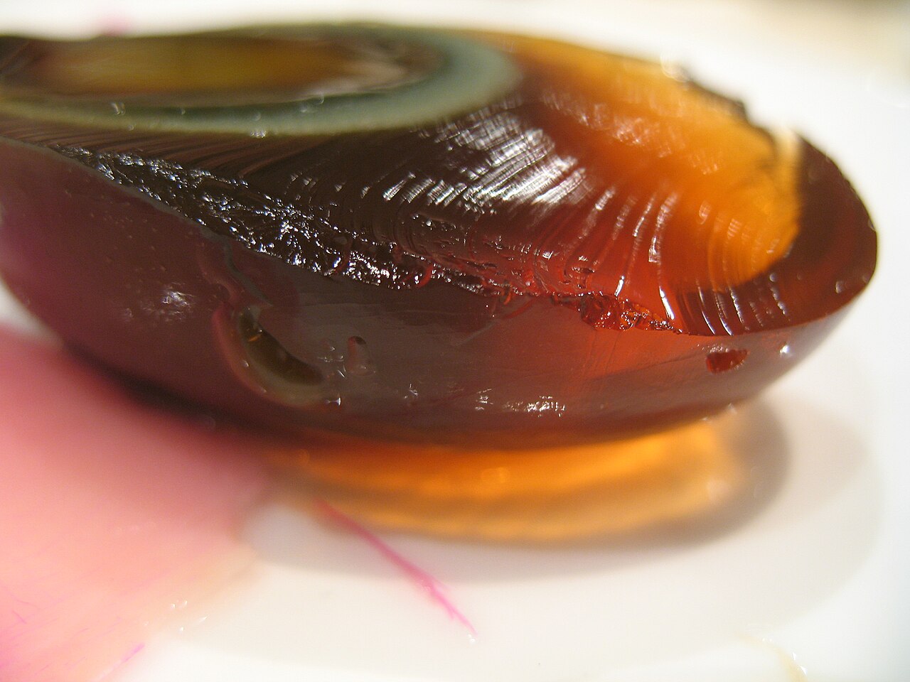 A century egg sliced open, showing its dark jelly-like white and gray-green yolk